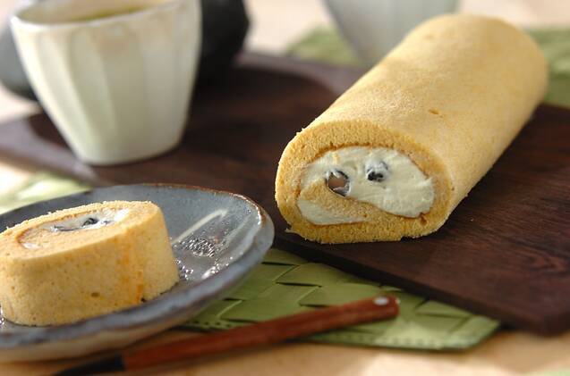 木製の盆と灰色の皿に盛り付けられた、きなこと黒豆のロールケーキ