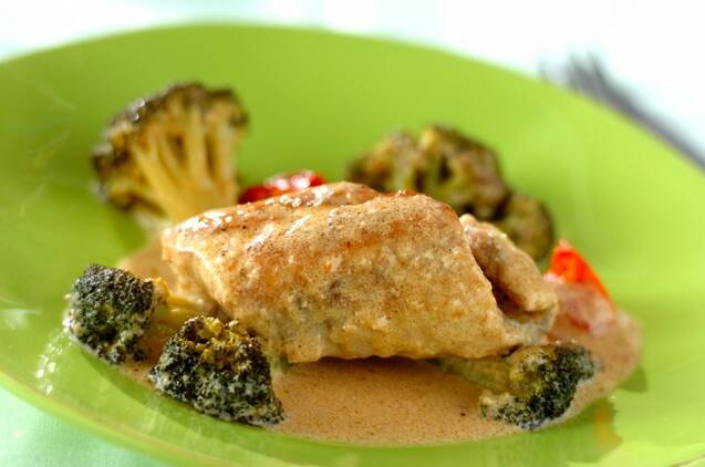 黄緑色の皿の上に盛り付けられた鯛のクリーム煮と付け合わせのブロッコリー