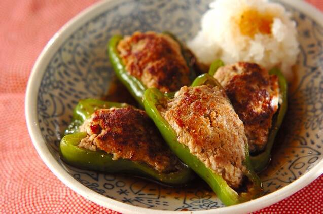 青い柄の皿に盛り付けられたピーマンの肉詰めと大根おろし