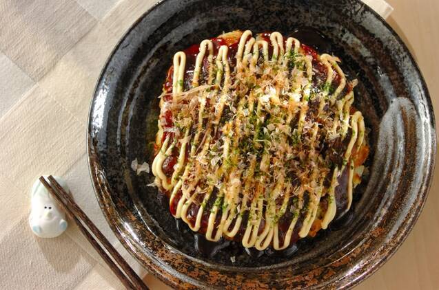 マヨネーズをたっぷりかけたお好み焼きをのせた黒いお皿