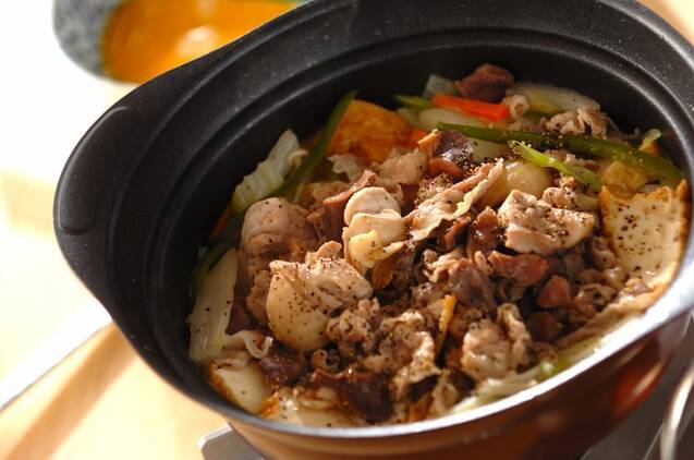 黒い小鍋に入っている鶏もも肉と砂肝、白菜や厚揚げ入りの煮物