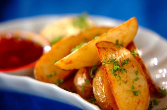 白い器に盛りつけ、パセリのみじん切りを散らしたフライドポテト