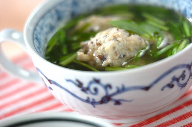 取っ手付きのカップに入っているせりときくらげの鶏団子スープ