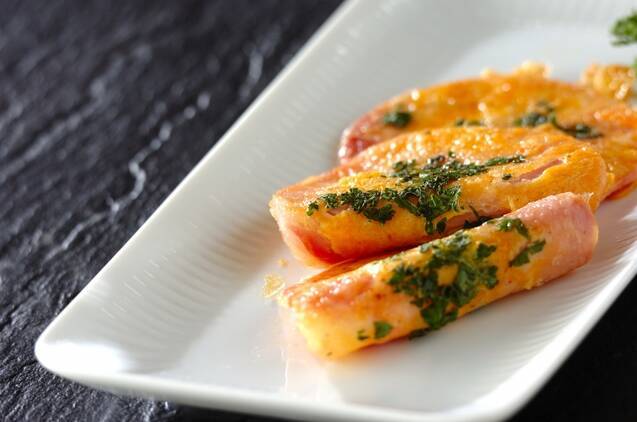 白い長皿に盛りつけられている、刻みパセリと厚切りハムのピカタ