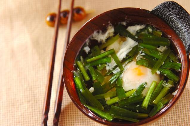 片手の茶色い器に盛られた、ニラとおとし卵のスープ