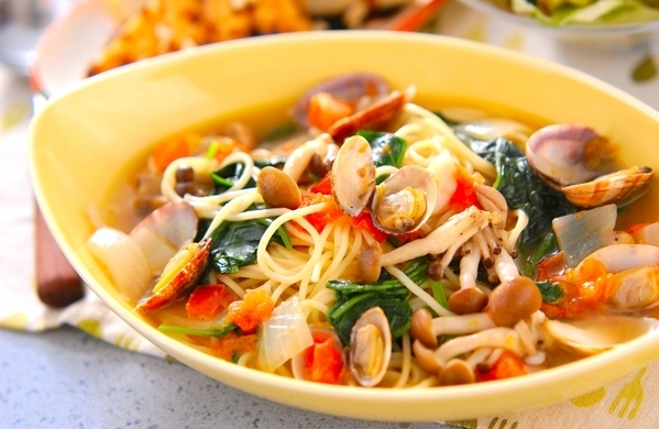 黄色い皿に盛り付けたあさりとほうれん草のトマトスープパスタ