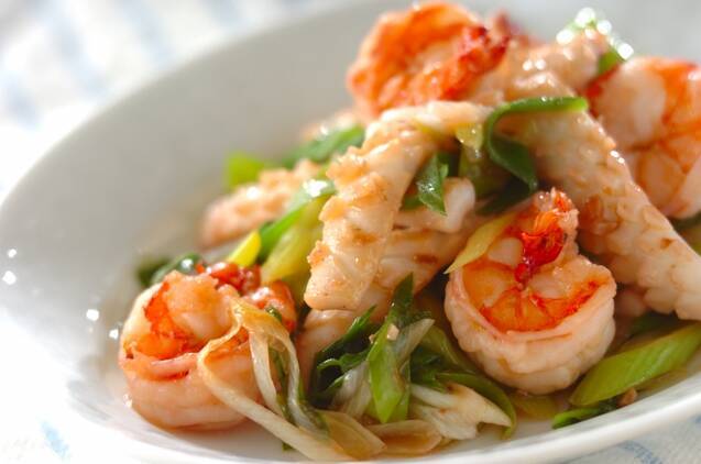 長細くて白いお皿に魚介とネギのガーリック炒めが盛ってある