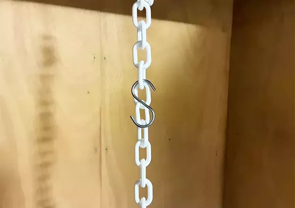「ダイソーで買った白い鎖、つっぱり棒にかけると　戸棚の収納スペースが増える『知恵』に感動」の画像