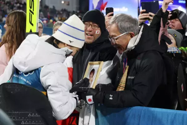 母の遺影に触れる丸山　五輪
