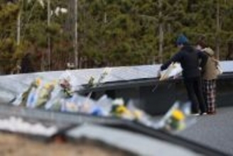 慰霊碑に触れる千葉夫妻