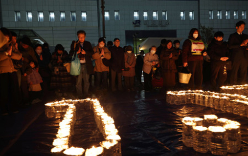 追悼行事で黙とうする人たち