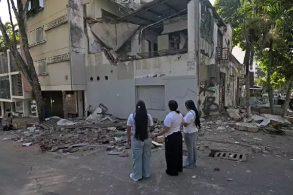 倒壊した建物を見詰める住民ら