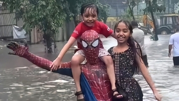 インドのスパイダーマンが豪雨で冠水した道路で困っている人々を助ける