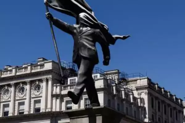 バンクシー新作、珍しい彫像作品　ロンドンにスーツ姿で旗掲げる人