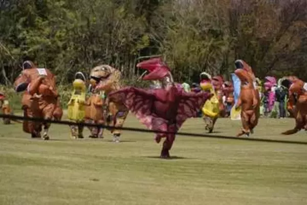 ティラノサウルスの着ぐるみレース　色とりどりの恐竜が疾走する中、一つだけ別のいきもの…「ひこうタイプは禁止！笑」「向かい風の時は不利」