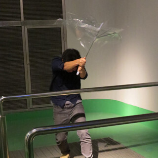 風の強い日に傘をさす場合、どの角度がもっとも楽なのかを体で検証する。