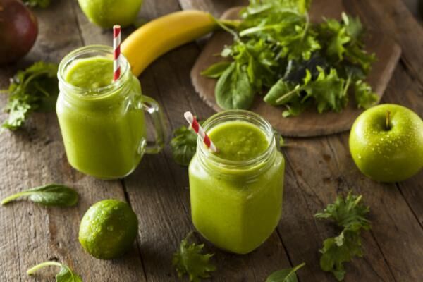 Two healthy green smoothies on wooden table