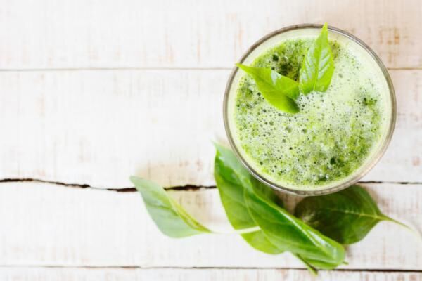 green herbal detox drink made of spinach on white wood