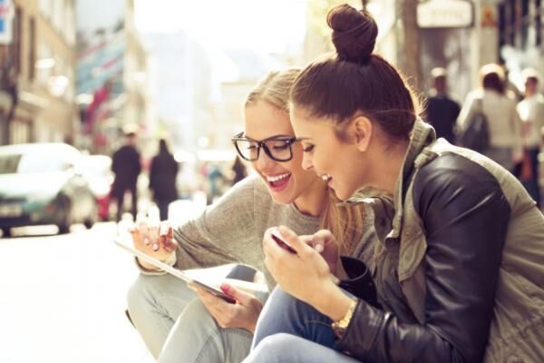 Two young women with tablet on street