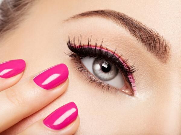 Closeup woman face with pink nails near eyes.