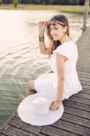 woman sitting on a dock with white dress