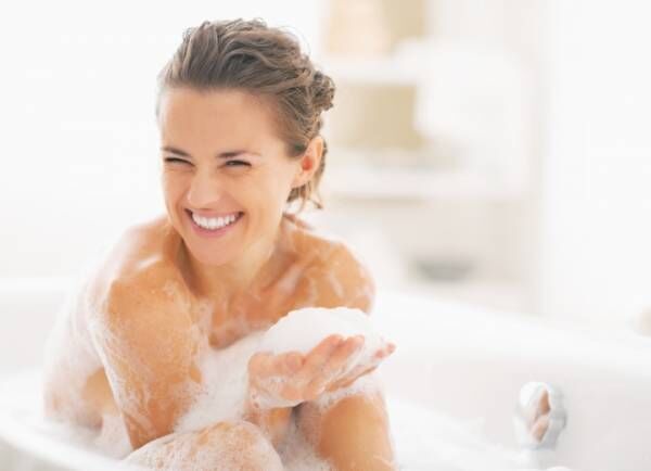 Young woman playing with foam in bathtub