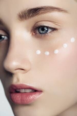 Beautiful woman with cream dots on the face