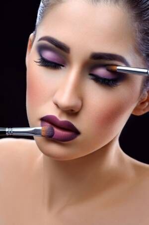 Young beautiful woman wearing professional makeup holding makeup