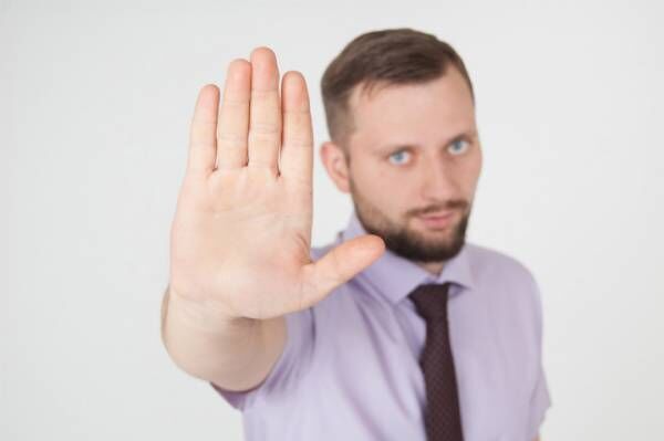 Stop sign concept, businessman showing refuse gesture.
