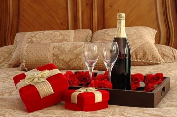 Romantic setting of wine and presents on a bed