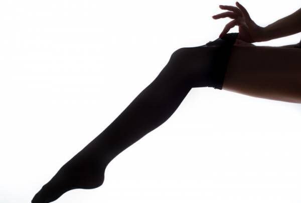 lady puts on stockings in silhouette