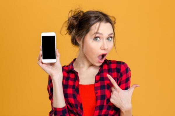 Amazed woman showing blank smartphone screen