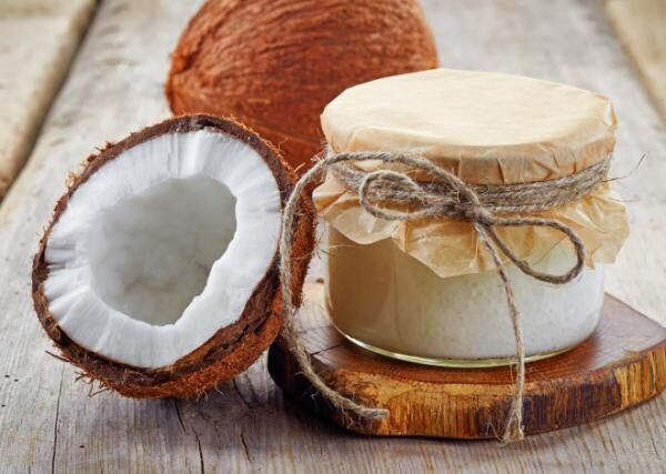 A coconut jar with coconut oil and coconuts sliced in half