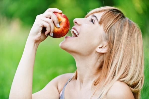 Profile of beautiful blonde girl about to bite a red apple