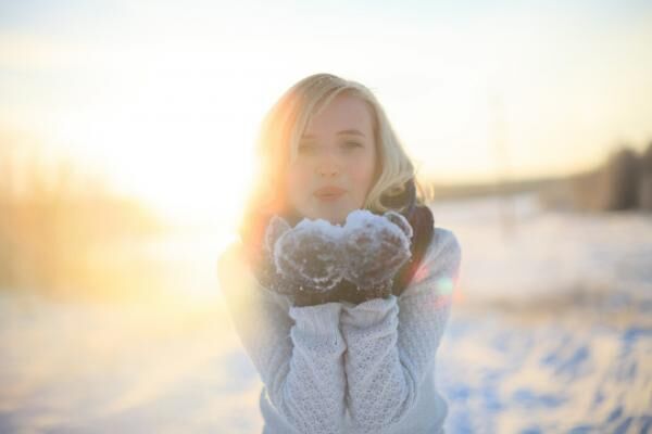 Beautiful blonde girl standing in winter snow-covered road