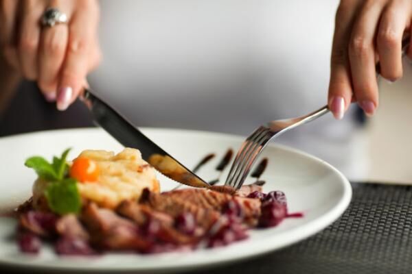 Woman using knife and fork to cut her dinner