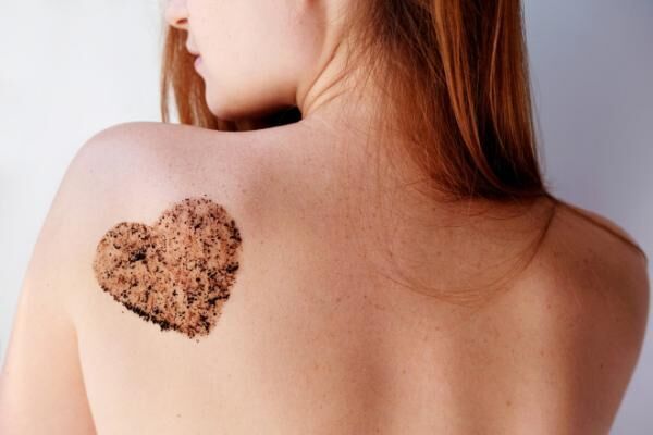 Woman with coffee scrub in a heart shape on back.