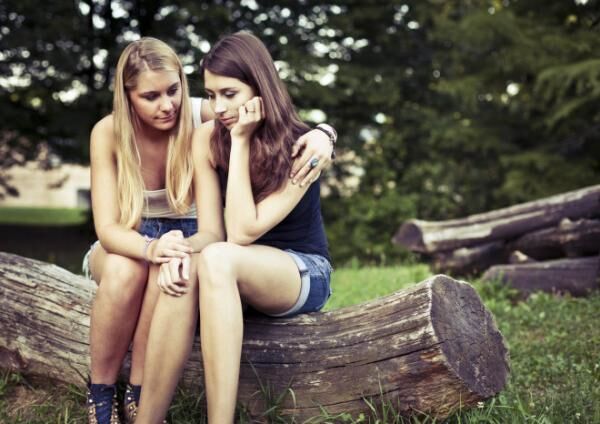 A teenager consoling her friend who looks sad