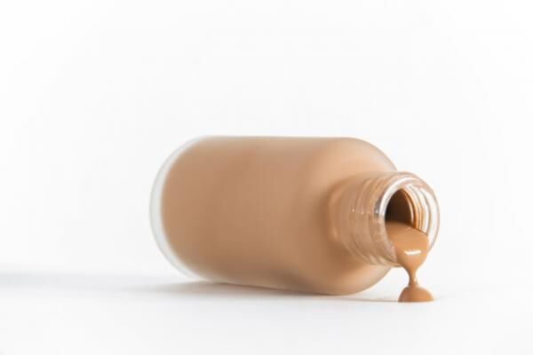 Isolated image of bottle of make-up on its side pouring out
