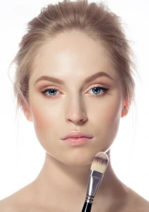 Portrait of young woman with make-up foundation brush