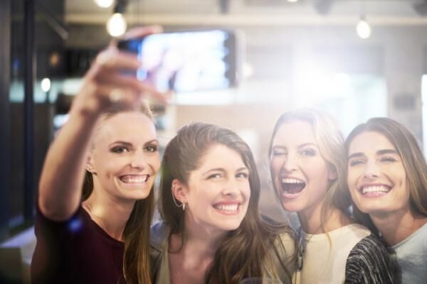 Happy women taking selfie on mobile phone in bar