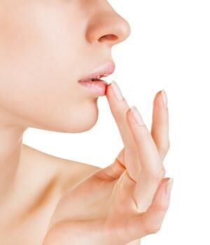 Woman applying lip balm on white
