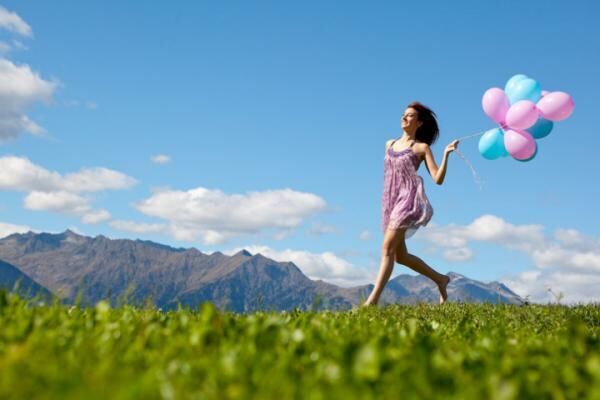 Woman wearing dress and running with balloons