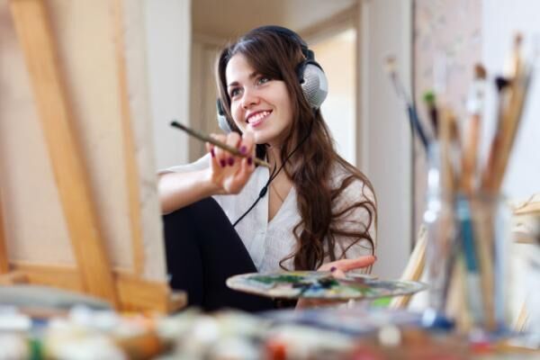 Long-haired artist in headphones paints picture
