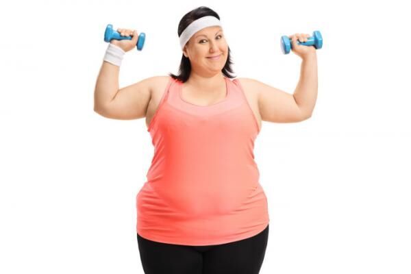 Overweight woman exercising with small dumbbells