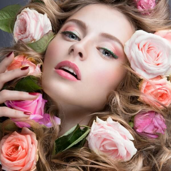 Headshot of Girl in full make up surrounded by pink roses