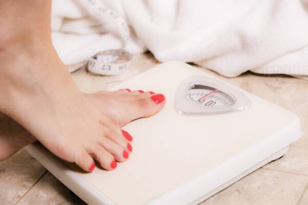 Healthy Lifestyle: Weight conscious woman steps on bathroom scale.