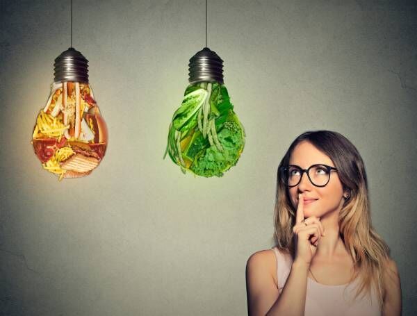 woman looking at junk food green vegetables shaped lightbulb