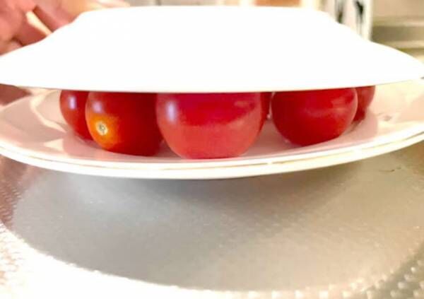プチトマトを２枚の皿で挟んでいる様子