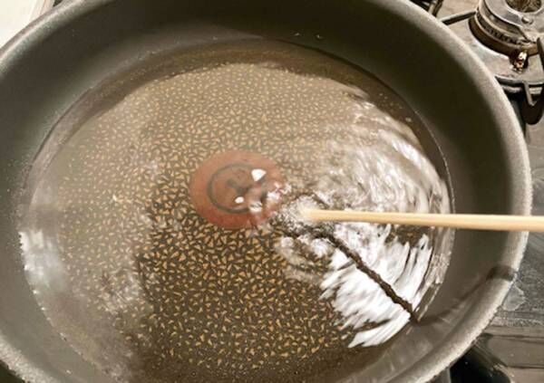 割り箸を揚げ油に入れて気泡が出るか確認している写真